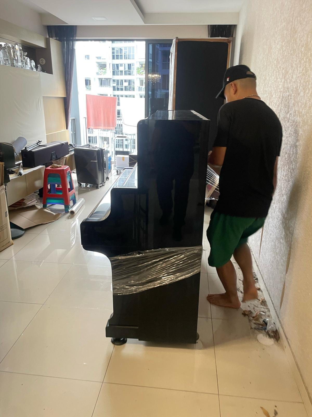 Upright piano being prepared for protected handling in a Singapore home