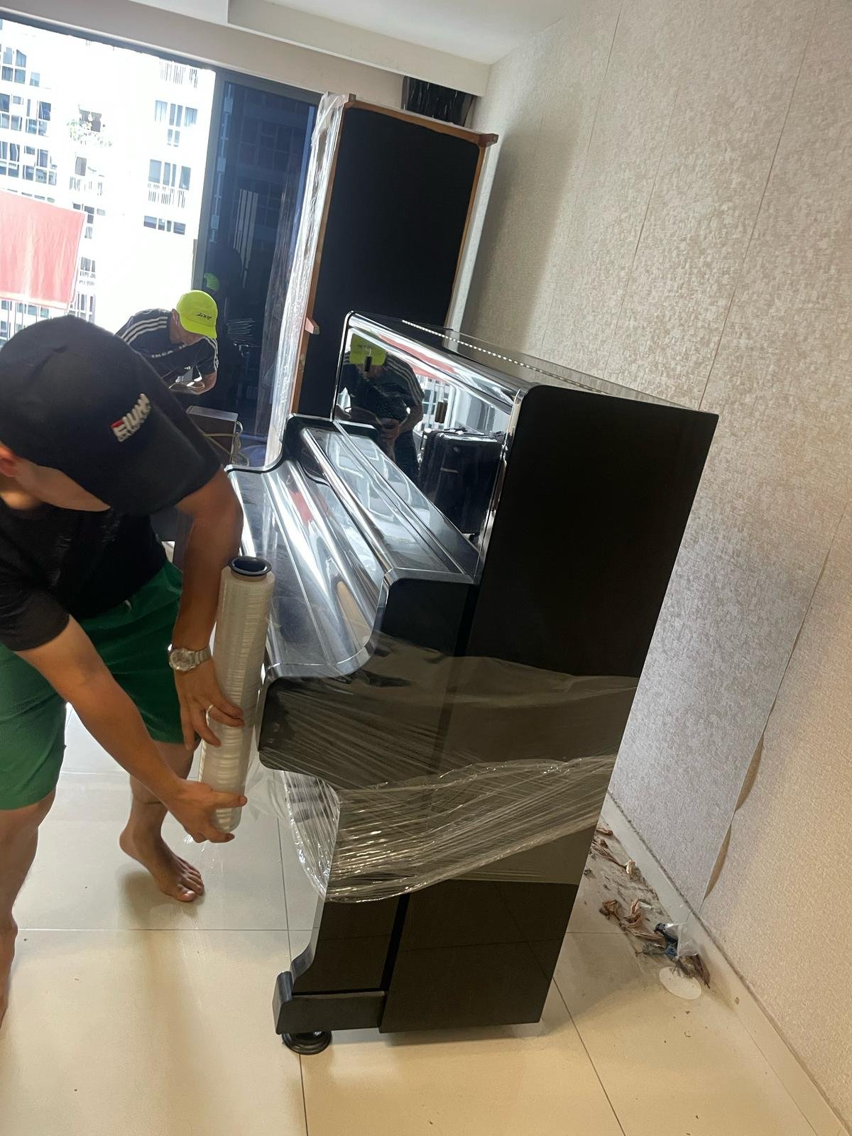 Upright piano receiving protective stretch wrapping before handling